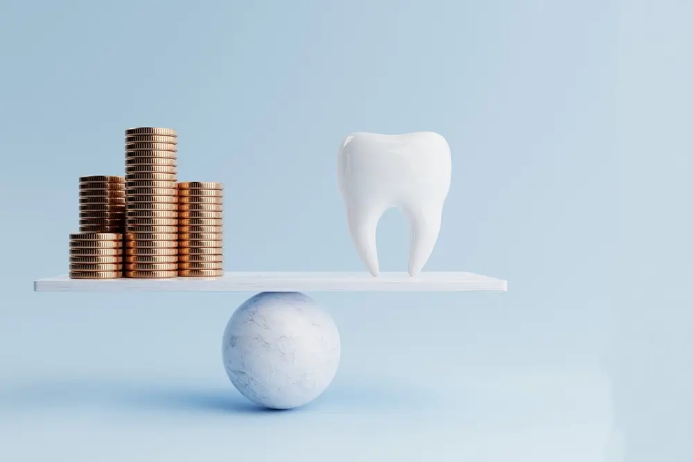Dental tooth and golden coin on balancing scale
